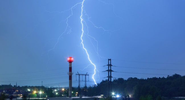 Lightning in the night sky over the boiler house and power lines