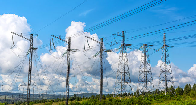 High voltage transmission towers row. Electrical energy wire on the rural landscape background.